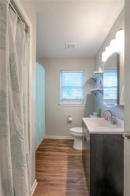 bathroom with visible vents, wood finished floors, vanity, baseboards, and toilet