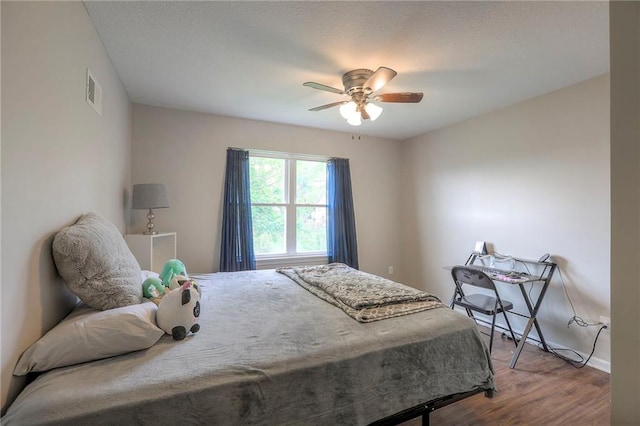 bedroom with baseboards, ceiling fan, visible vents, and wood finished floors