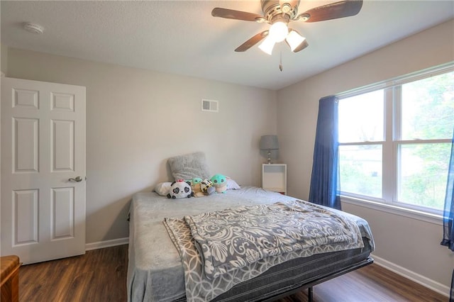bedroom with visible vents, baseboards, wood finished floors, and multiple windows