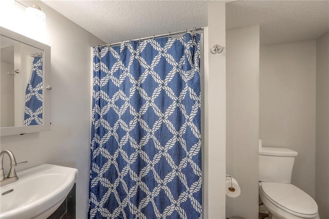 full bath with toilet, a textured ceiling, curtained shower, and a sink