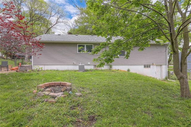 exterior space with a lawn, central AC unit, and an outdoor fire pit
