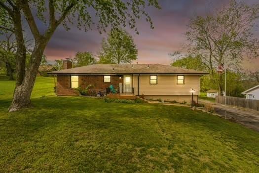 13956 Gibbs Rd, Bonner Springs, KS 66012 - back of property at dusk featuring a chimney and a yard