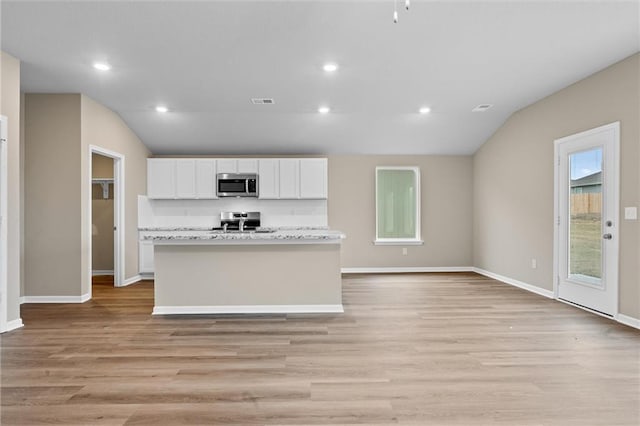 37839 W 207th Ter, Edgerton, KS 66021 - kitchen featuring stainless steel microwave, lofted ceiling, white cabinetry, a kitchen island with sink, and light wood-style floors