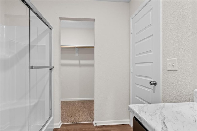 37854 W 207th Ter, Edgerton, KS 66021 - bathroom with a shower stall, vanity, wood finished floors, a textured wall, and a spacious closet