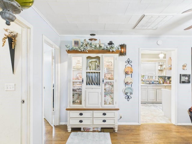 corridor featuring crown molding, light wood finished floors, and baseboards