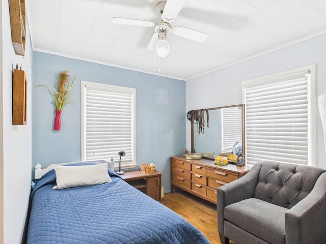 bedroom with crown molding, a ceiling fan, and wood finished floors