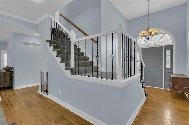 entryway featuring an inviting chandelier, a wealth of natural light, hardwood / wood-style flooring, and visible vents