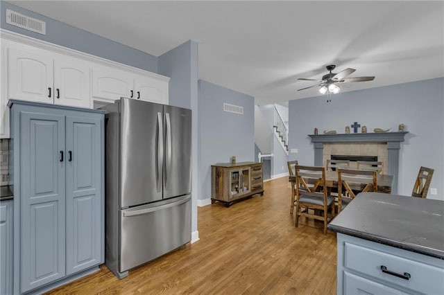 kitchen with white cabinets, ceiling fan, freestanding refrigerator, a tile fireplace, and visible vents