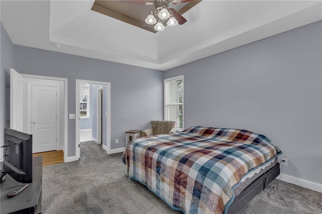 bedroom featuring a ceiling fan, baseboards, carpet, and a tray ceiling