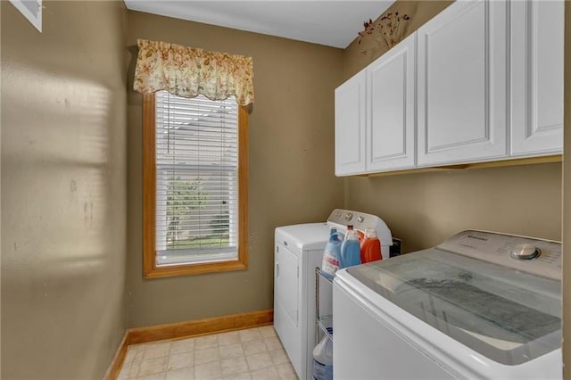 laundry area featuring cabinet space, baseboards, a healthy amount of sunlight, and washer and clothes dryer
