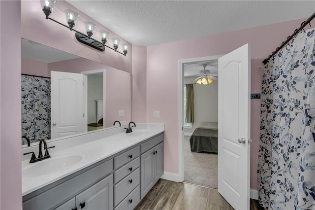 bathroom with a sink, a textured ceiling, ensuite bathroom, and double vanity