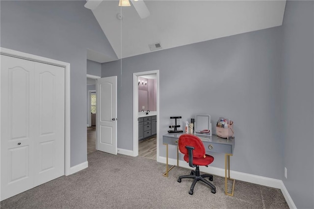 carpeted office space with ceiling fan, visible vents, a sink, baseboards, and high vaulted ceiling