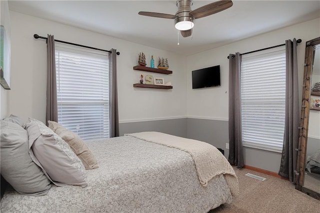 carpeted bedroom with baseboards, multiple windows, ceiling fan, and visible vents