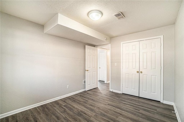 3552 S Lynn St, Independence, MO 64055 - unfurnished bedroom featuring visible vents, a textured ceiling, baseboards, and dark wood finished floors