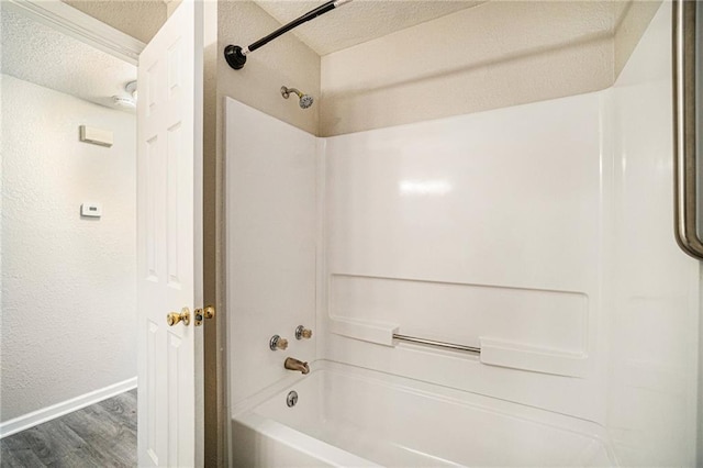 3552 S Lynn St, Independence, MO 64055 - bathroom with wood finished floors, tub / shower combination, baseboards, and a textured ceiling