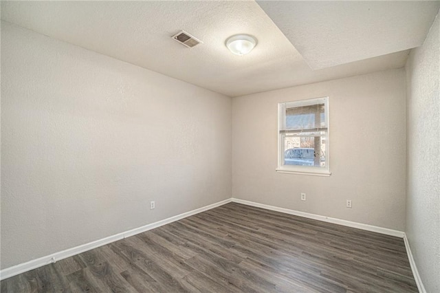 3552 S Lynn St, Independence, MO 64055 - empty room with dark wood-style floors, visible vents, baseboards, and a textured ceiling