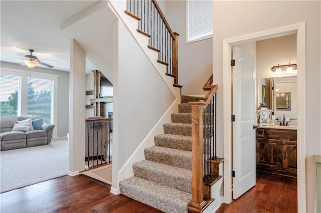 staircase with baseboards, ceiling fan, wood finished floors, and a fireplace