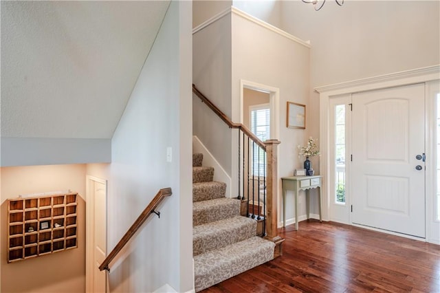 foyer featuring baseboards, stairs, and wood finished floors
