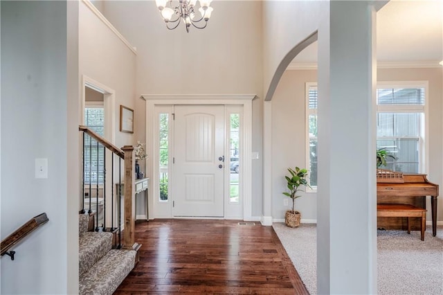 entryway with stairs, arched walkways, an inviting chandelier, and plenty of natural light