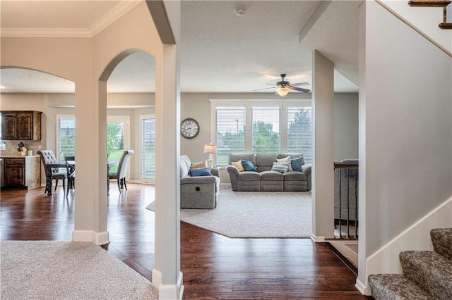living room with ceiling fan, ornamental molding, dark wood-style flooring, and stairs