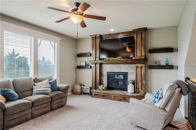 carpeted living area with a tiled fireplace, a ceiling fan, and baseboards