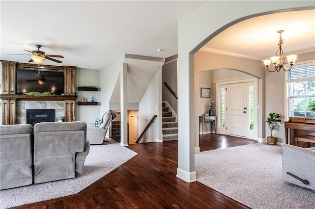 living area with ornamental molding, stairs, dark wood-style flooring, arched walkways, and a premium fireplace