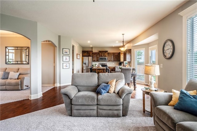living area with dark wood-style flooring, arched walkways, baseboards, and recessed lighting