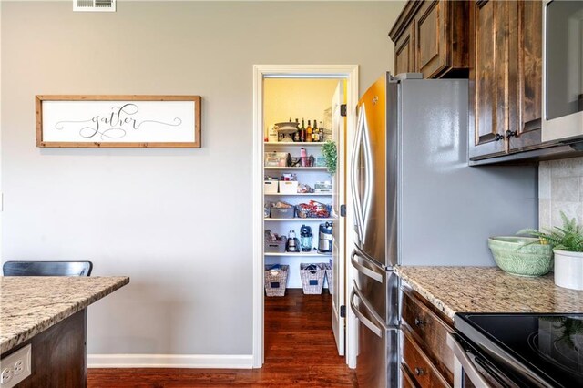 kitchen with dark brown cabinets, light stone countertops, baseboards, dark wood-type flooring, and visible vents