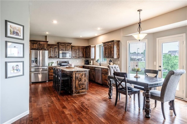kitchen featuring decorative backsplash, dark brown cabinetry, a center island, a sink, and stainless steel appliances