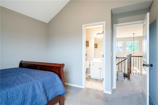 bedroom with carpet floors, baseboards, connected bathroom, and lofted ceiling