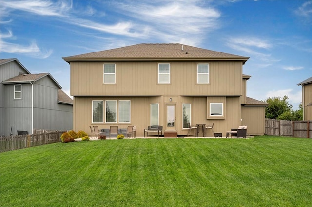 rear view of property featuring a fenced backyard, a yard, a patio area, and roof with shingles
