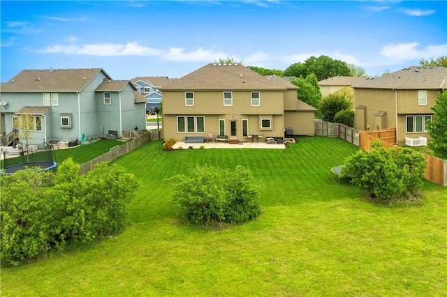 back of property with a fenced backyard, a patio area, a lawn, a trampoline, and a residential view