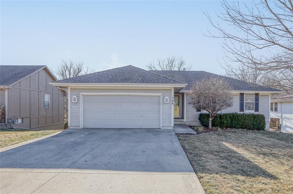 ranch-style home featuring an attached garage, concrete driveway, and roof with shingles