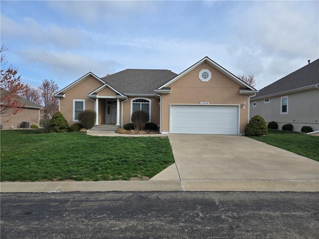 ranch-style house with stucco siding, a front lawn, concrete driveway, and an attached garage