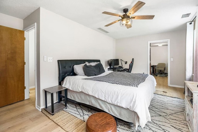 bedroom featuring baseboards, a ceiling fan, visible vents, and light wood-style floors