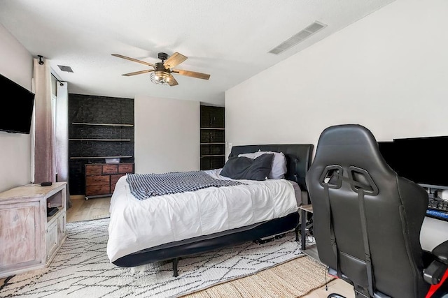 bedroom with light wood finished floors, visible vents, and a ceiling fan