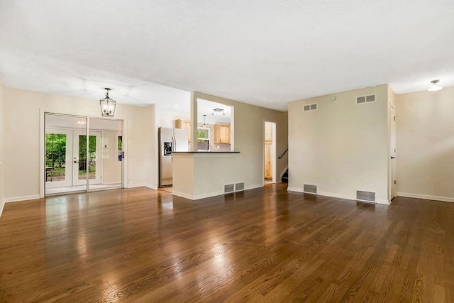 unfurnished living room with visible vents, stairs, and dark wood-type flooring