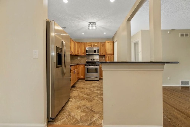 kitchen featuring visible vents, appliances with stainless steel finishes, dark countertops, and tasteful backsplash