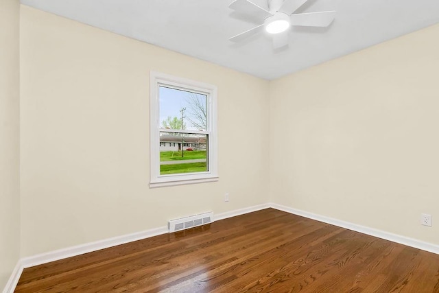 unfurnished room with baseboards, dark wood-style floors, and visible vents