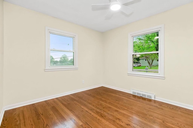 spare room featuring a ceiling fan, baseboards, visible vents, and wood finished floors