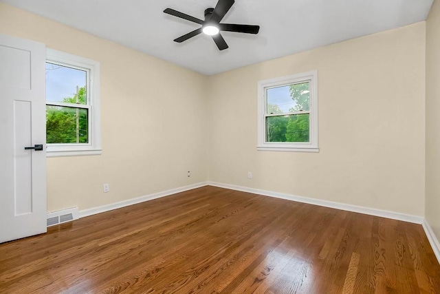 spare room with baseboards, a ceiling fan, wood finished floors, and visible vents