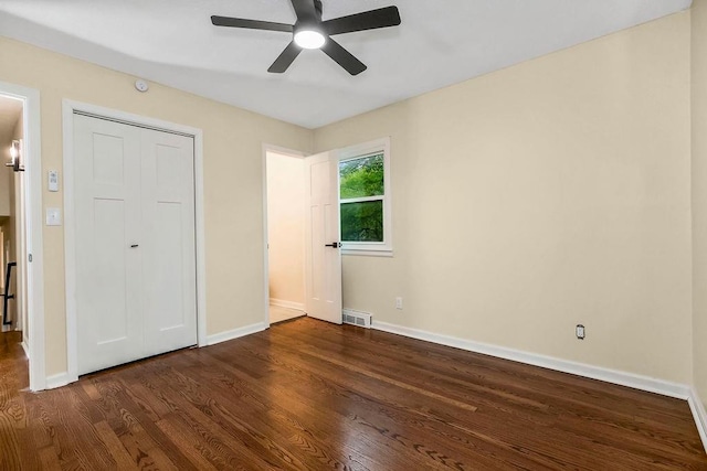 unfurnished bedroom with baseboards, dark wood-style flooring, and visible vents