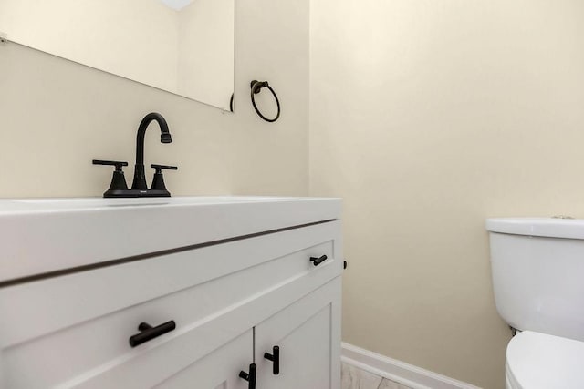 half bathroom with vanity, baseboards, toilet, and marble finish floor