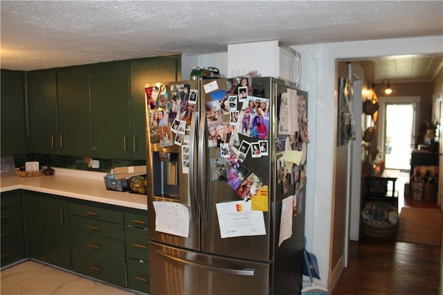 kitchen with green cabinets, stainless steel fridge with ice dispenser, light countertops, and a textured ceiling