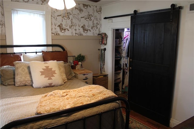 bedroom featuring a wainscoted wall, a closet, a barn door, visible vents, and wallpapered walls