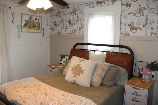 bedroom featuring wallpapered walls, a ceiling fan, and wainscoting