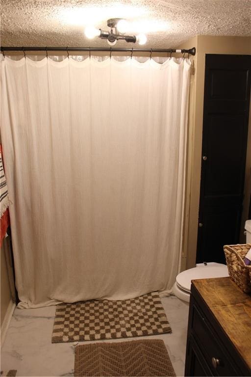 bathroom featuring marble finish floor, toilet, a shower with curtain, and a textured ceiling