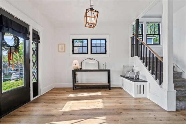 entrance foyer with baseboards, wood finished floors, stairs, and a notable chandelier