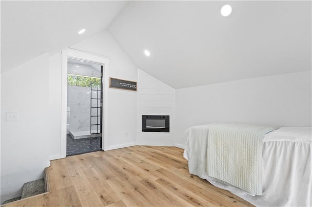 bedroom with vaulted ceiling, heating unit, wood finished floors, a fireplace, and recessed lighting