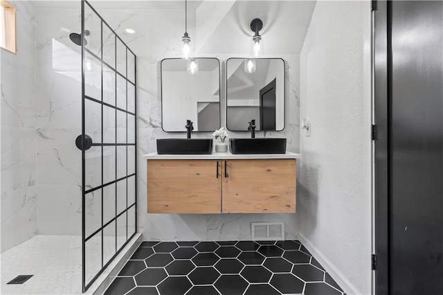 bathroom featuring double vanity, visible vents, a marble finish shower, and a sink